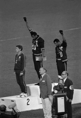 Extending gloved hands skyward in racial protest, U.S. athletes Tommie Smith, center, and John Carlos stare downward during the playing of the Star Spangled Banner after Smith received the gold and Carlos the bronze for the 200 meter run at the Summer Olympic Games in Mexico City on Oct. 16, 1968. Australian silver medalist Peter Norman is at left. (AP Photo)